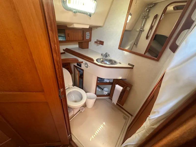 Slide: The Image of Island Packet 420 2002 yacht bathroom with wooden cabinetry, sink, toilet, and shower. - 24
