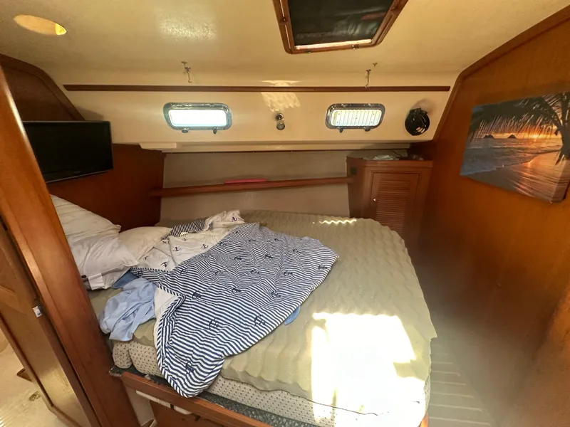 Slide: The Image of Island Packet 420 2002 yacht cabin with bed, portholes, and wooden interior. - 26