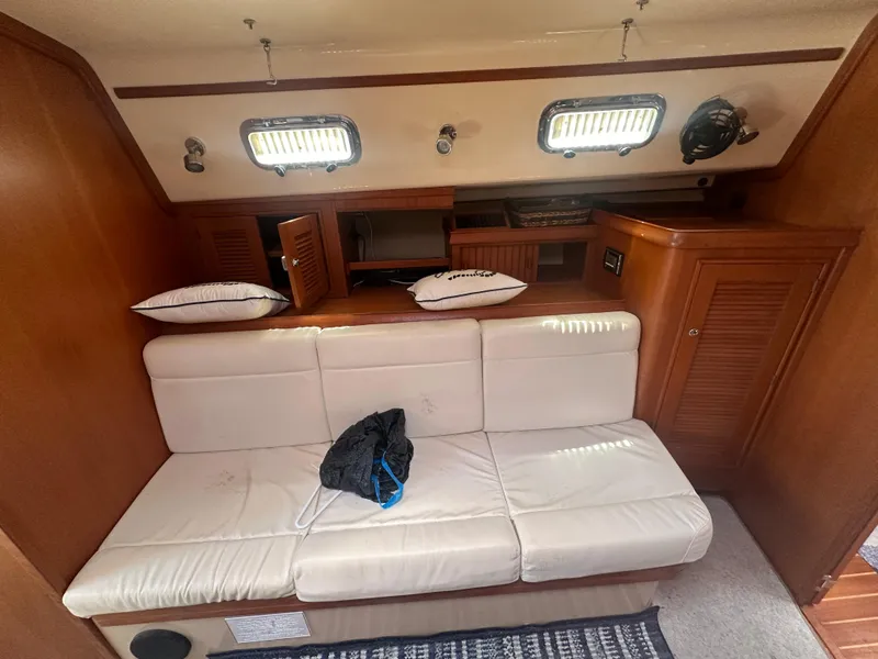 Slide: The Image of Interior of 2002 Island Packet 420 sailboat with white leather seating and wooden cabinetry. - 28