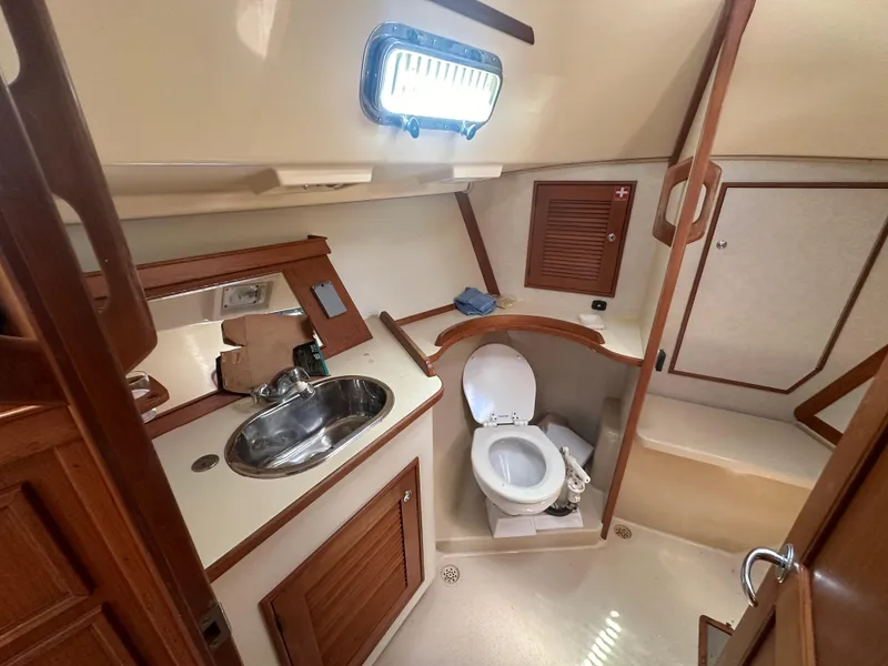 Slide: The Image of 2002 Island Packet 420 yacht bathroom with sink, toilet, and storage cabinets. - 42