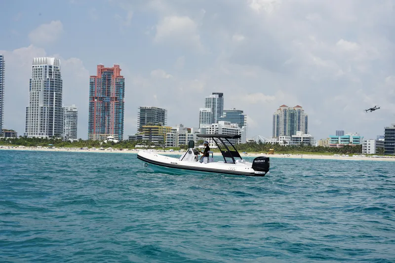 Slide: The Image of Aqvaboats Luxrib 22 (2025) cruising near a city skyline on a sunny day. - 10