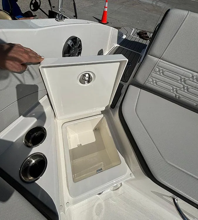 Slide: The Image of 2024 Sea Ray SPX 210 boat interior with open storage compartment and cup holders. - 4