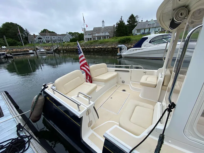 Slide: The Image of 2013 MJM 36z Downeast boat docked, featuring spacious seating and an American flag. - 9