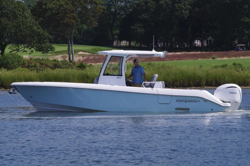 Slide: The Image of 2025 Everglades 285 Center Console boat cruising on a calm lake. - 2
