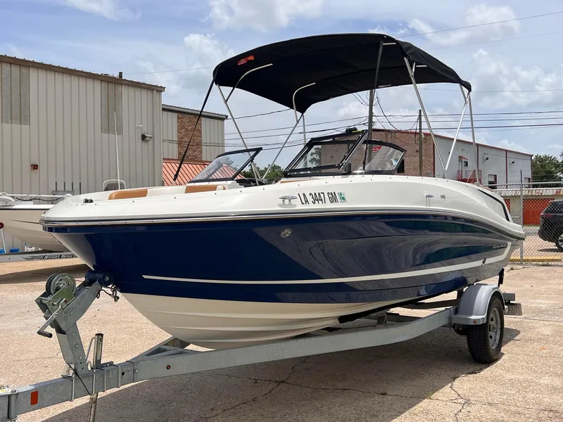 Slide: The Image of 2021 Bayliner VR5 Bowrider I/O boat on a trailer in a marina. - 2