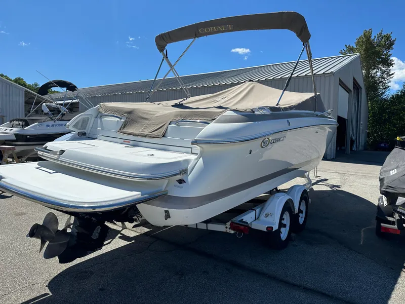 Slide: The Image of 2003 Cobalt 262 boat on a trailer, covered and parked outdoors. - 2