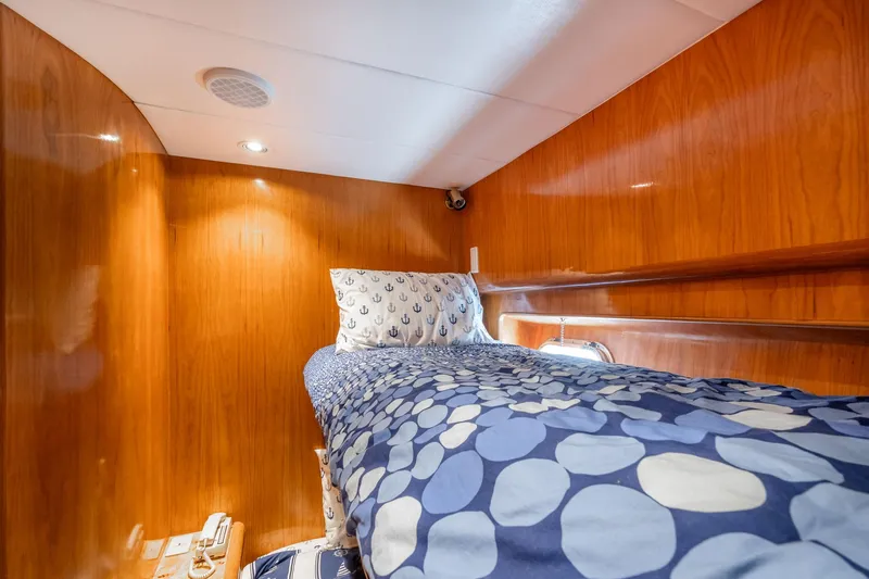 Slide: The Image of Cozy cabin interior of 1999 Vitech 68' Pilothouse yacht with wooden paneling and patterned bedding. - 38