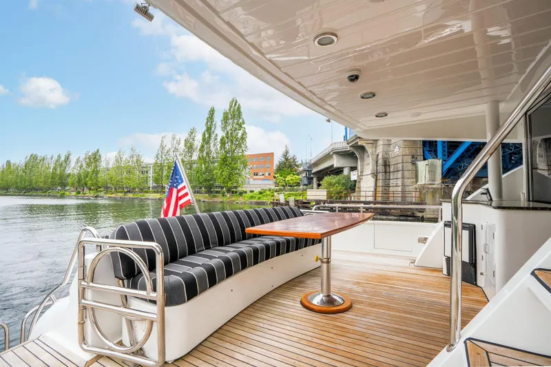 Slide: The Image of Outdoor seating area on 1999 Vitech 68' Pilothouse yacht with American flag and scenic river view. - 4