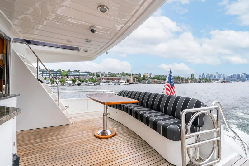 Slide: The Image of Luxurious 1999 Vitech 68' Pilothouse yacht deck with seating, table, and scenic waterfront view. - 5