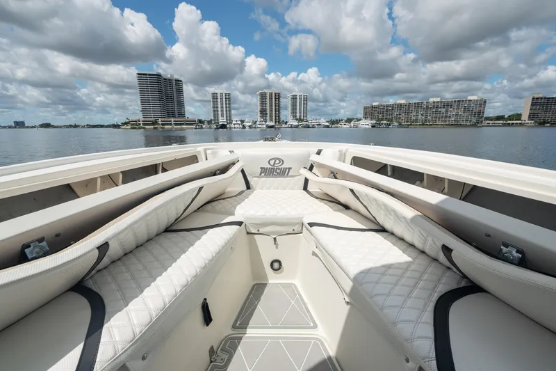 Slide: The Image of 2000 Pursuit 2870 Center Console boat with cushioned seating, docked near waterfront buildings. - 21