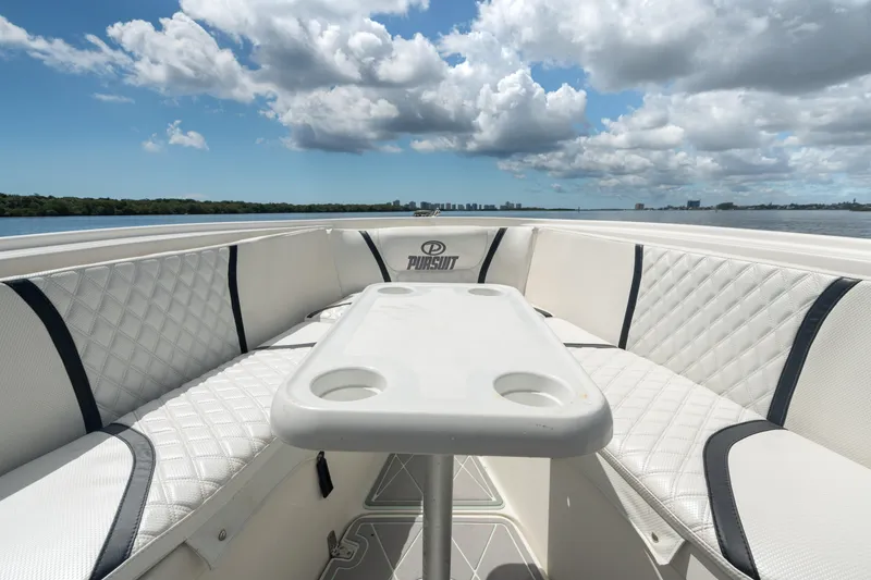 Slide: The Image of 2000 Pursuit 2870 Center Console boat with cushioned seating and table on a sunny day. - 22