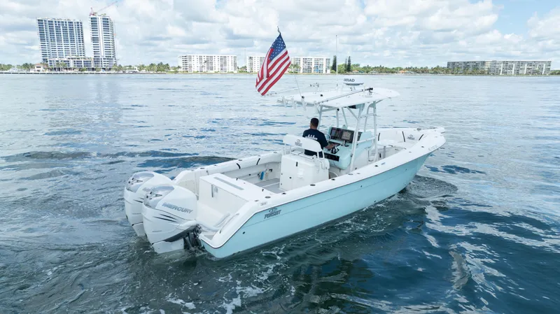 Slide: The Image of 2000 Pursuit 2870 Center Console boat cruising on water with American flag. - 3