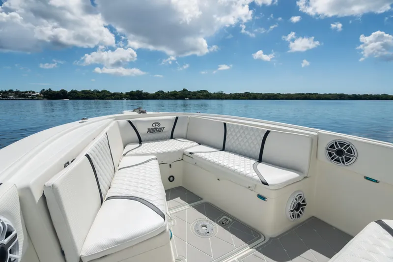 Slide: The Image of 2000 Pursuit 2870 Center Console boat with cushioned seating on a calm lake. - 9