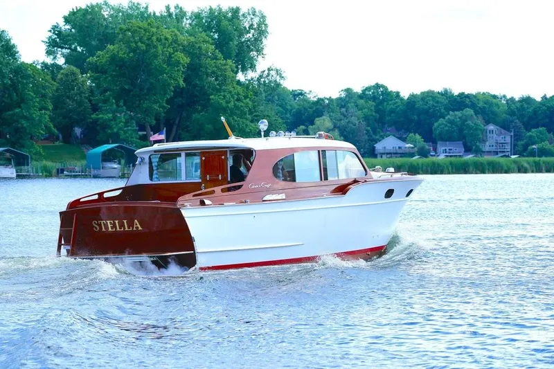 Slide: The Image of 1954 Chris-Craft Sedan Cruiser "Stella" on a serene lake with lush green shoreline. - 2
