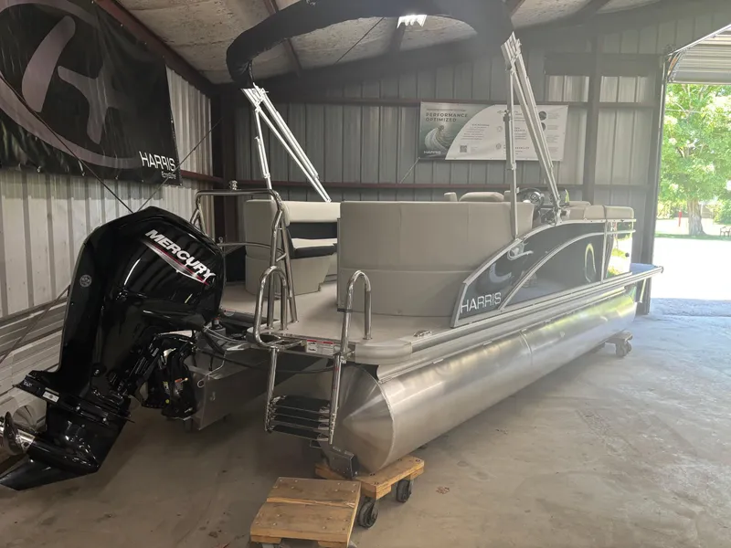 Slide: The Image of 2025 Harris Breeze 210 pontoon boat with Mercury outboard motor in storage shed. - 2