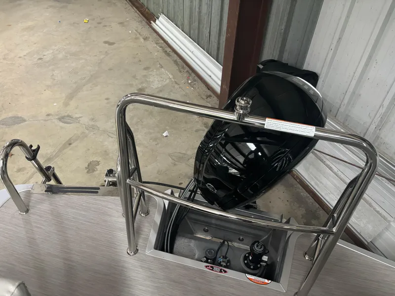 Slide: The Image of 2025 Harris Breeze 210 pontoon boat with outboard motor in a storage facility. - 6