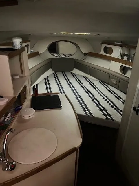 Slide: The Image of 1999 Four Winns 258 Vista cabin interior with striped bedding and kitchenette. - 4