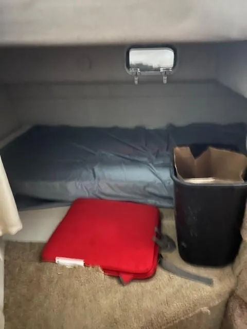 Slide: The Image of 1999 Four Winns 258 Vista cabin interior with bed, red cushion, and trash bin. - 5