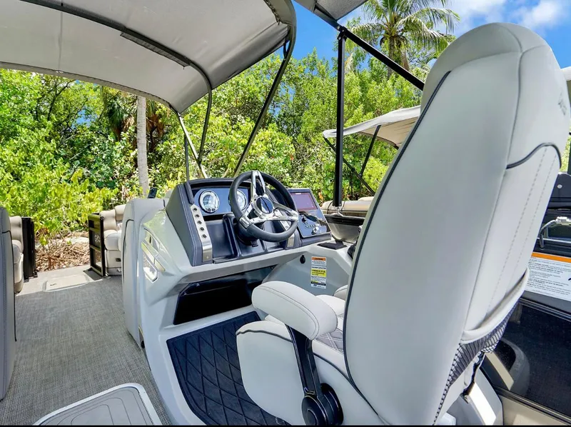 Slide: The Image of 2022 Barletta Lusso 25UC boat interior with steering wheel, luxurious seating, and canopy. - 5