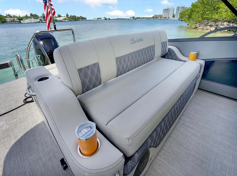 Slide: The Image of 2022 Barletta Lusso 25UC boat interior with plush seating and cup holders on a sunny day. - 6