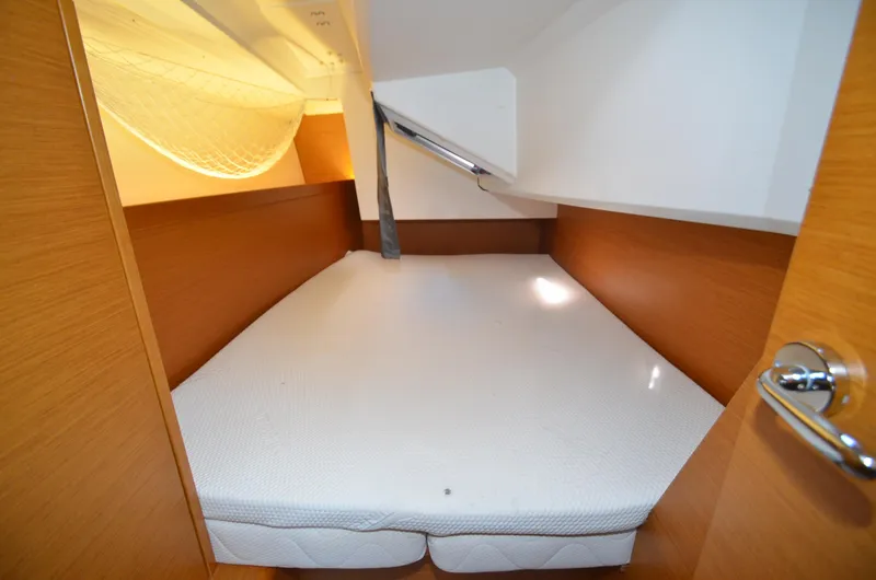 Slide: The Image of 2015 Jeanneau 349 cabin interior with a cozy bed and wooden finish. - 27