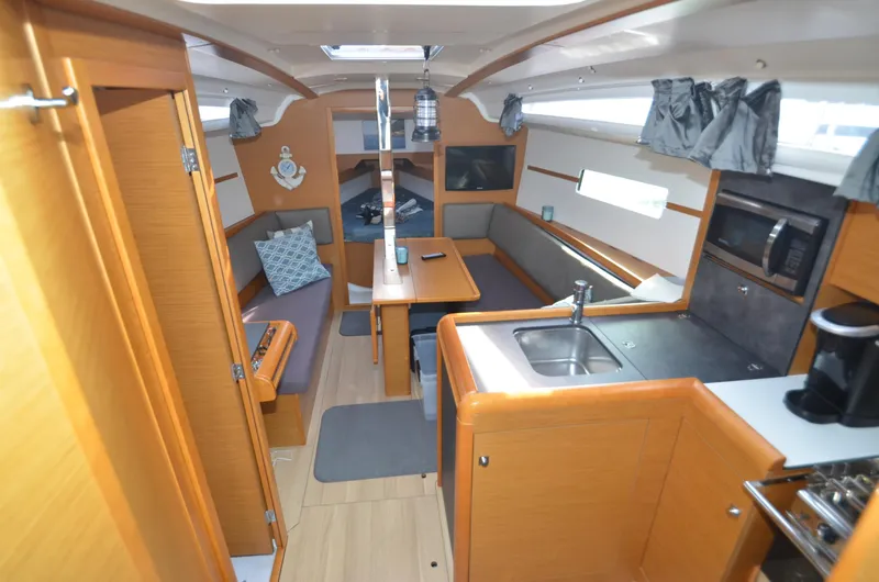 Slide: The Image of 2015 Jeanneau 349 interior with kitchen, seating area, and wooden cabinetry. - 3