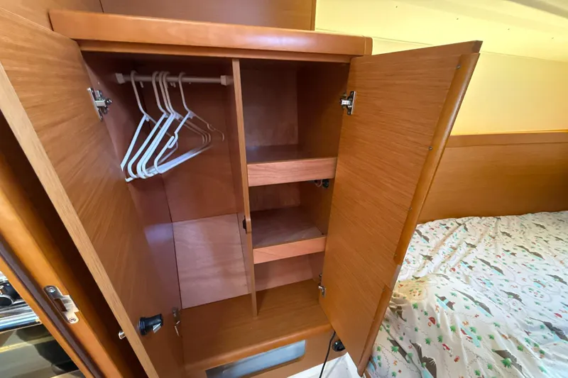 Slide: The Image of 2015 Jeanneau 349 interior closet with hangers and shelves, next to a bed. - 30