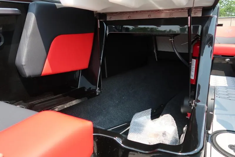 Slide: The Image of 2025 MasterCraft NXT20 interior storage compartment with red and black seating. - 30
