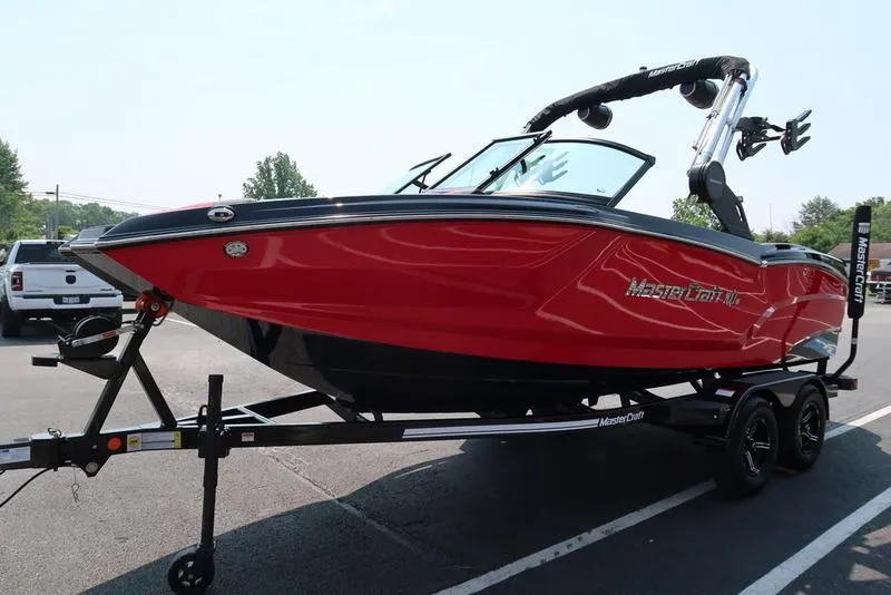Slide: The Image of 2025 MasterCraft NXT20 boat in vibrant red on a trailer, parked outdoors. - 4