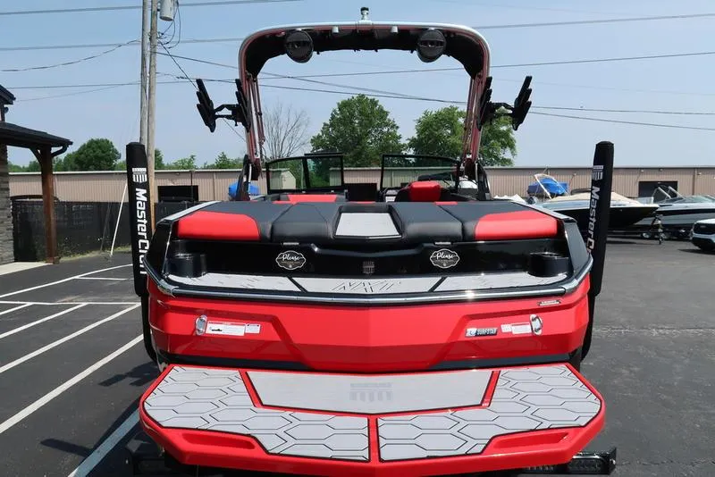 Slide: The Image of 2025 MasterCraft NXT20 boat, red and black, rear view in parking lot. - 6