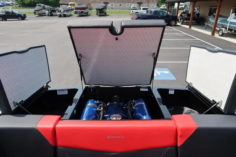 Slide: The Image of 2025 MasterCraft NXT20 boat engine compartment with open hatches in a parking lot. - 8