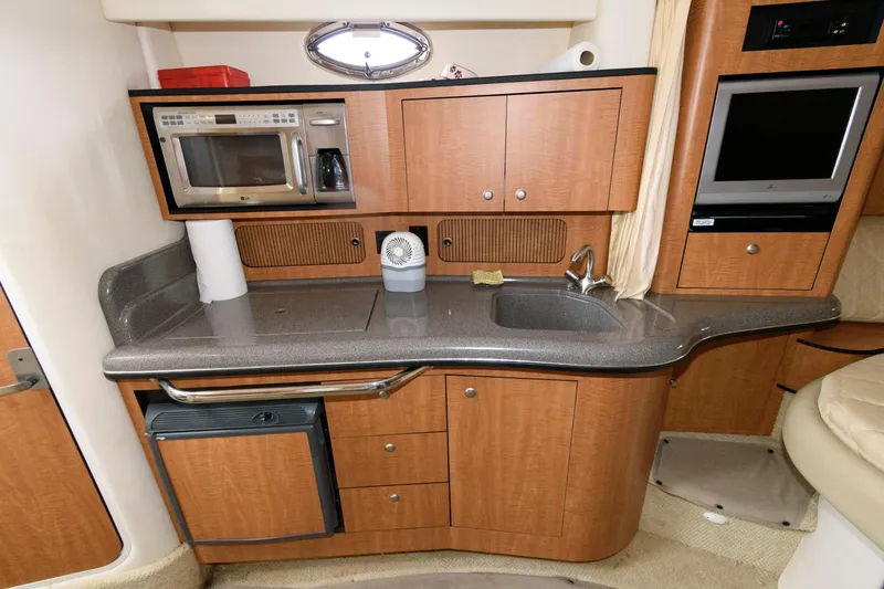 Slide: The Image of 2006 Sea Ray 320 Sundancer galley with microwave, sink, and storage cabinets. - 14