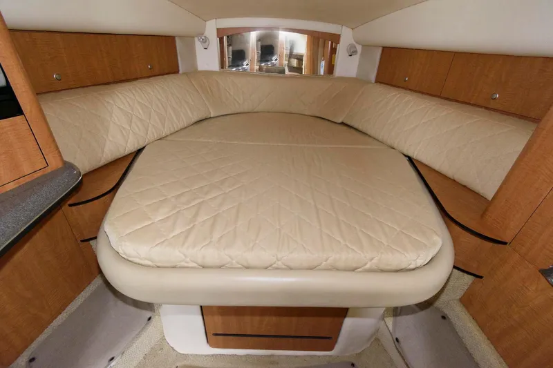 Slide: The Image of 2006 Sea Ray 320 Sundancer cabin interior with beige bedding and wooden cabinetry. - 15