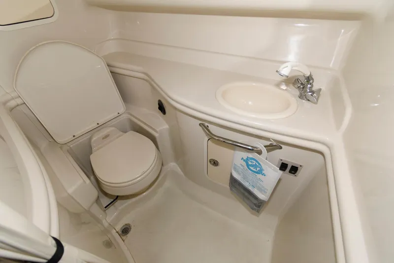 Slide: The Image of 2006 Sea Ray 320 Sundancer bathroom with toilet, sink, and storage. - 17