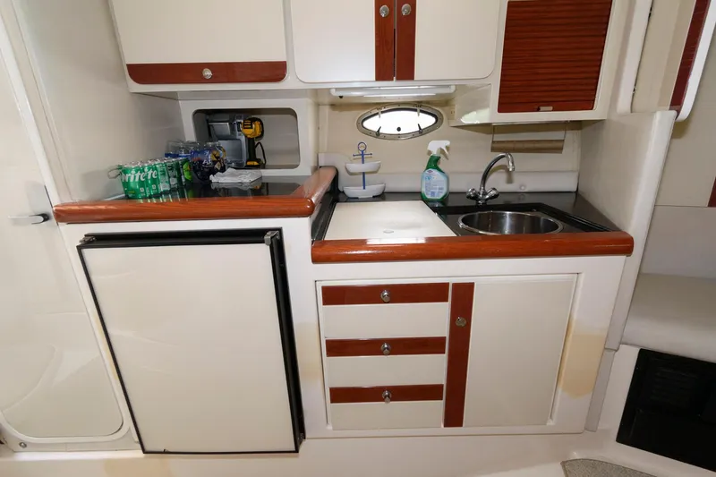 Slide: The Image of 1997 Donzi 3250 LXC boat kitchenette with sink, fridge, and storage cabinets. - 14