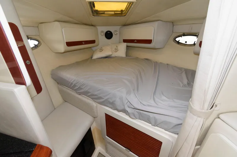 Slide: The Image of 1997 Donzi 3250 LXC cabin interior with bed, white upholstery, and wooden accents. - 15