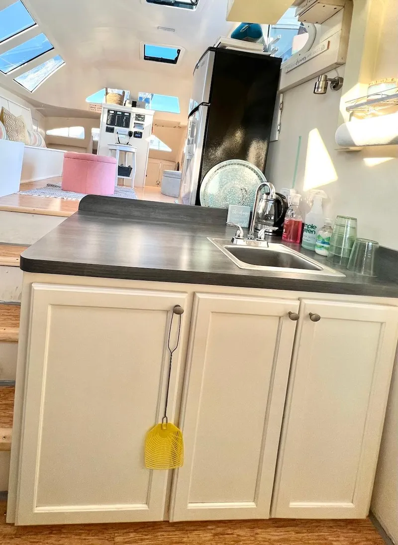 Slide: The Image of Modern kitchen area in a 2007 Farrier F-41 catamaran with white cabinets and black countertop. - 20