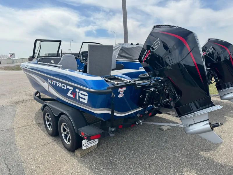 Slide: The Image of 2024 Nitro ZV19 Sport boat with dual engines on a trailer, parked outdoors. - 2