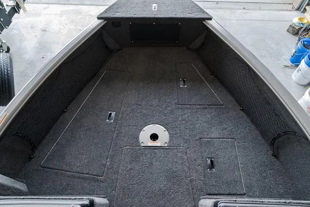Slide: The Image of 2024 Lund 1775 Impact XS Sport boat interior with carpeted deck and storage compartments. - 18