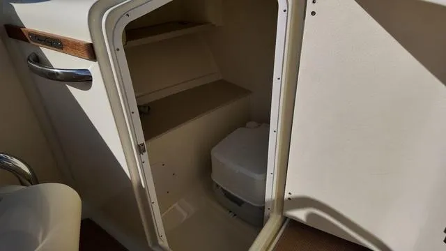 Slide: The Image of 2017 Chris-Craft 27 Launch boat interior with beige seating and wood accents. - 23