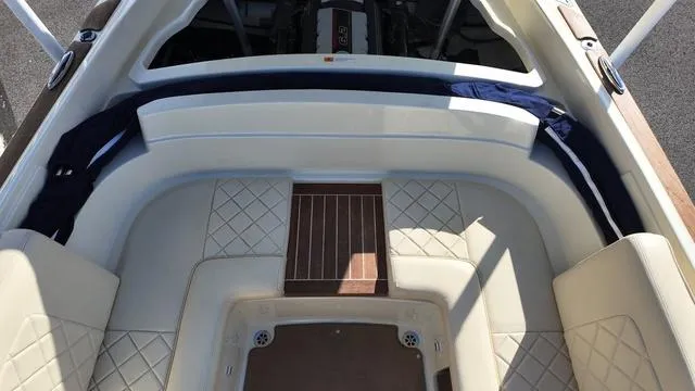 Slide: The Image of 2017 Chris-Craft 27 Launch boat interior with beige seating and wood accents. - 32