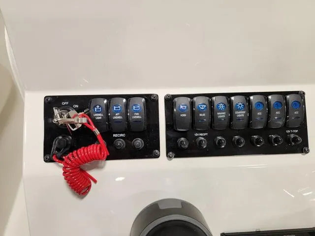Slide: The Image of Control panel of 2023 Stingray 173CC boat with various switches and red safety cord. - 13