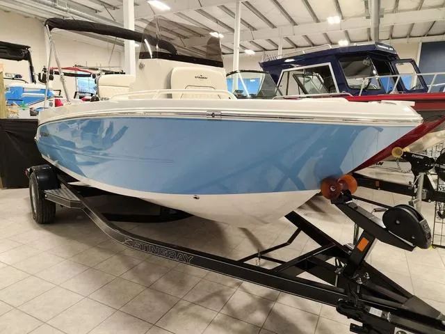 Slide: The Image of 2023 Stingray 173CC boat in showroom, blue and white hull on trailer. - 4