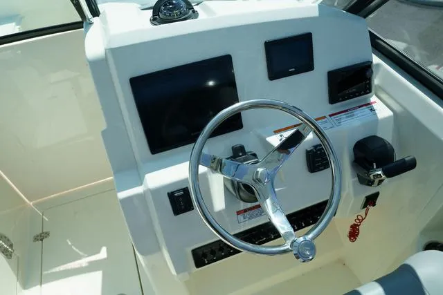 Slide: The Image of 2024 Cobia 240 DC boat dashboard with steering wheel and control panel. - 19