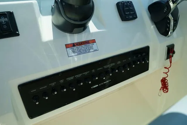 Slide: The Image of 2024 Cobia 240 DC boat dashboard with control panel and warning label. - 22