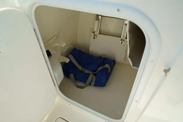 Slide: The Image of Storage compartment in 2024 Cobia 240 DC boat with blue duffel bag. - 23