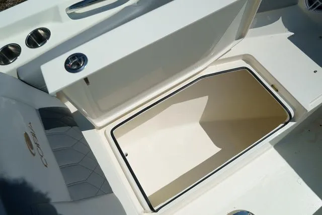 Slide: The Image of 2024 Cobia 240 DC boat storage compartment with open lid and cup holders. - 27