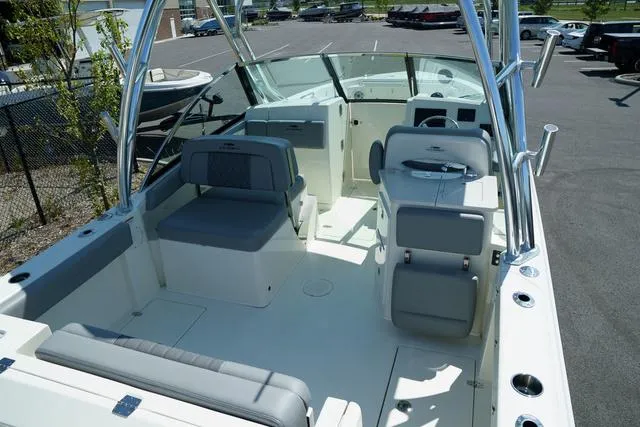 Slide: The Image of 2024 Cobia 240 DC boat interior with seating and helm, parked in a lot. - 3