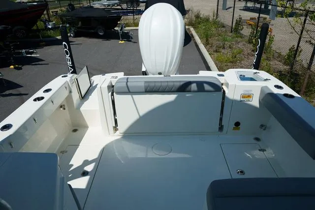 Slide: The Image of 2024 Cobia 240 DC boat interior with seating and storage, docked outdoors. - 4