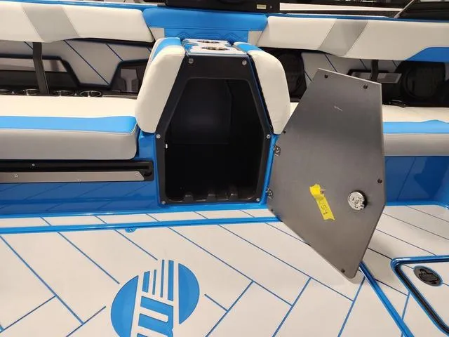 Slide: The Image of 2023 Malibu 26 LSV boat interior with open storage compartment and blue-white seating. - 16
